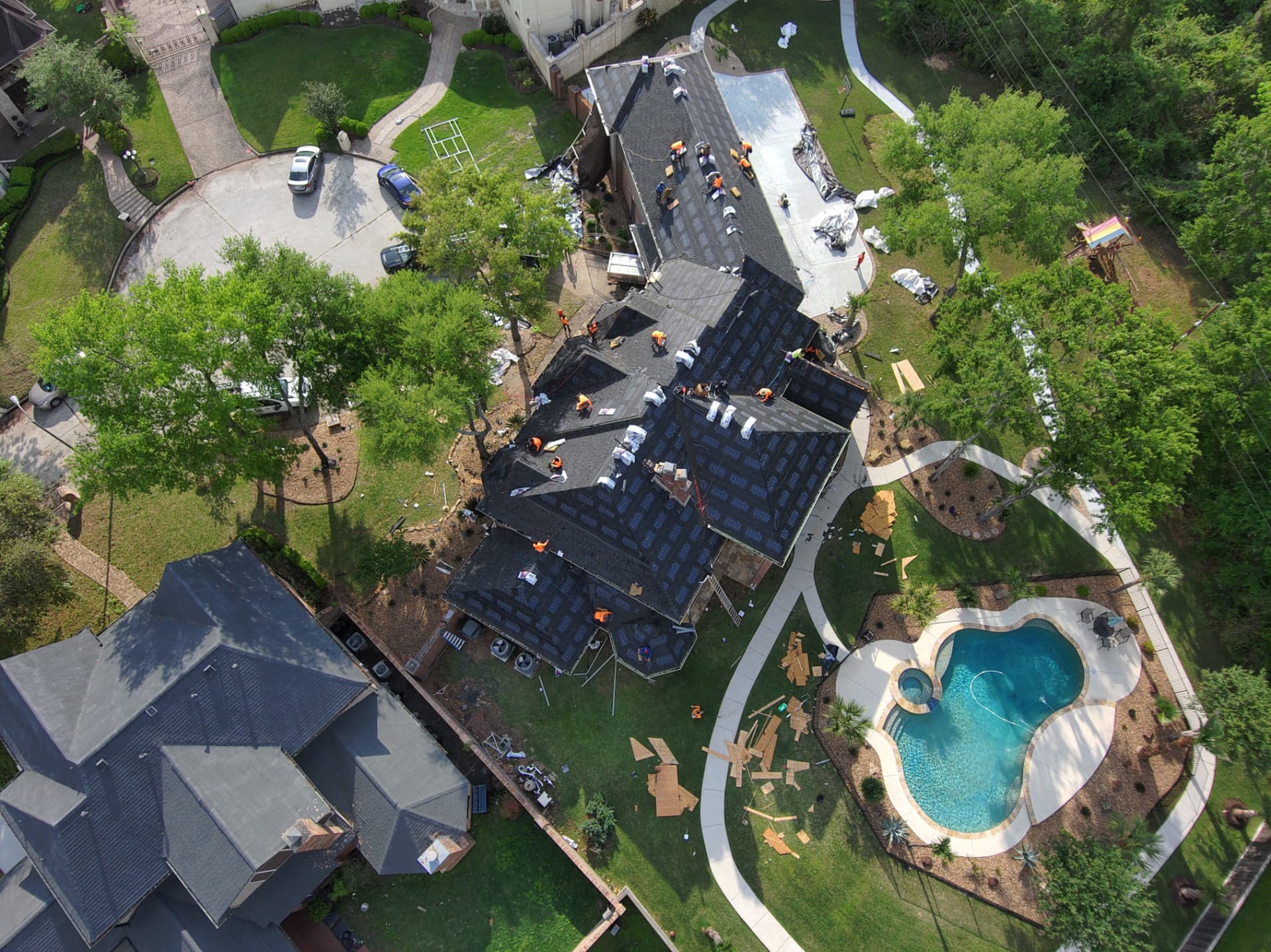Aerial drone photo of a full roof replacement with synthetic underlayment installed and crews working