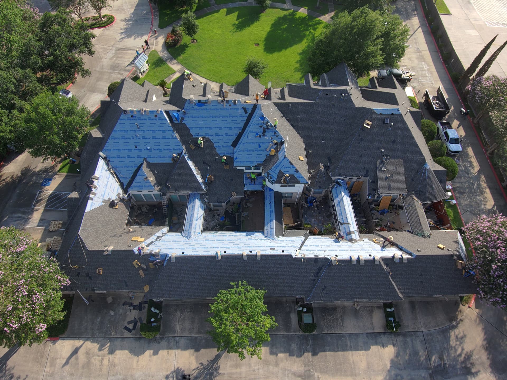 Drone photo of a commercial-scale roof replacement with crew working in sections