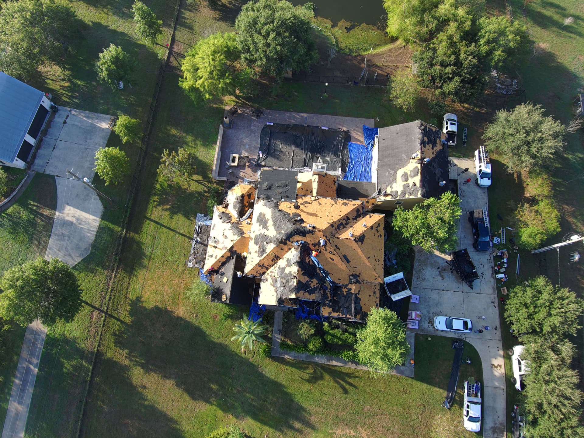 Drone shot of a roof tear-off with tarps protecting the property below