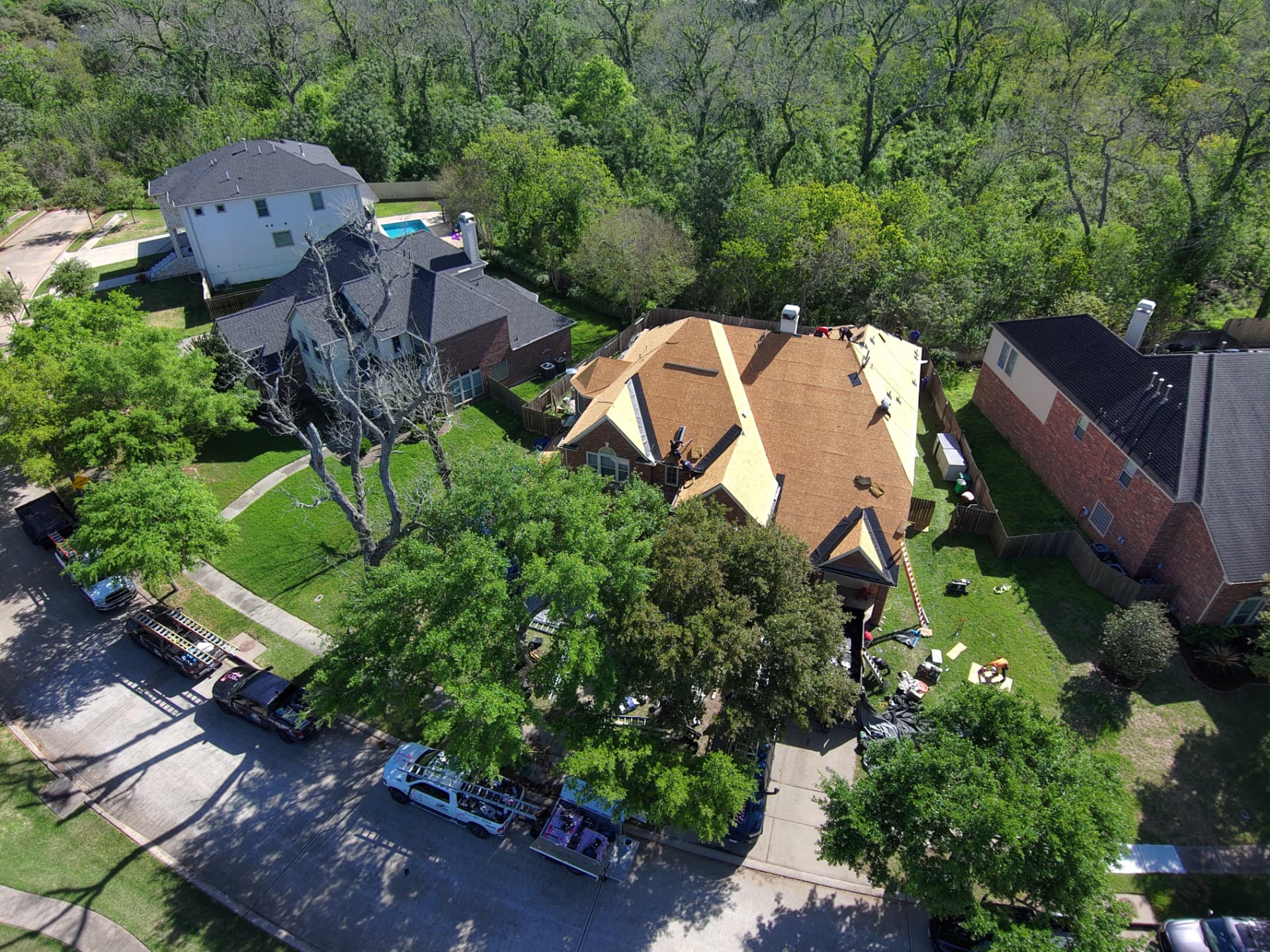 Drone view of a full shingle roof replacement in progress on a two-story Houston-area home